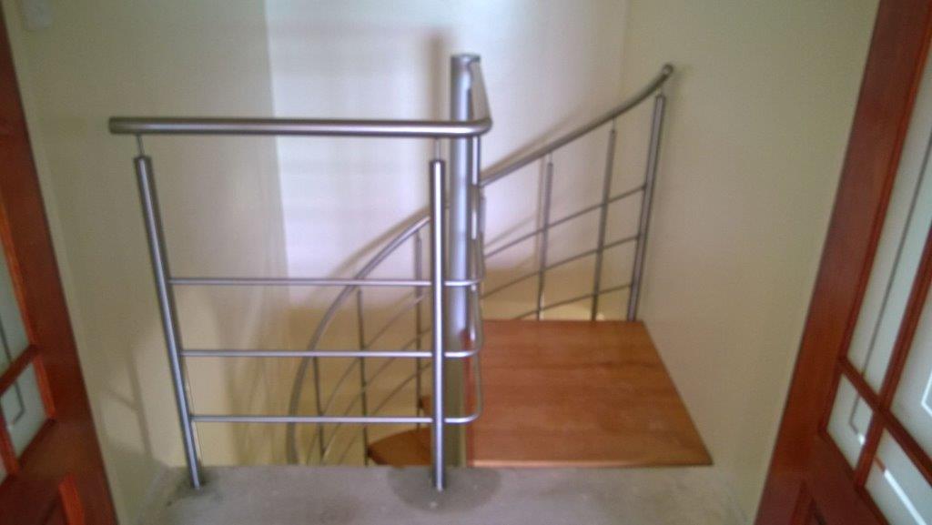 Landing of spiral staircase with stainless steel handrail.