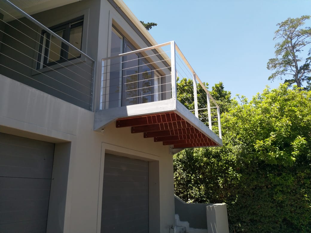A galvanized mild steel balcony with wood and a galvanized mild steel balustrade with stainless steel wires. 
