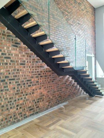 A mild steel staircase, painted black with stained French oak steps and glass balustrades. 